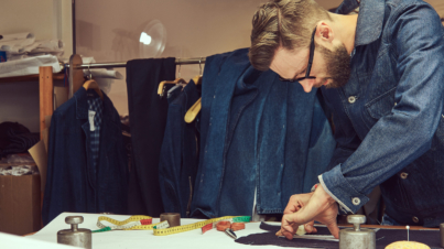 Handsome bearded tailor working with cloth samples at a sewing workshop.