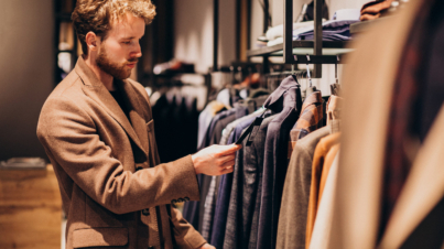 Young handsome man choosing cloth at shop